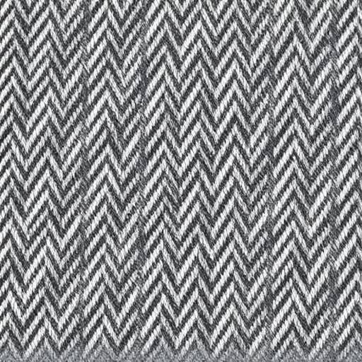 Close-up of a classic grey herringbone tweed fabric swatch with visible weave.